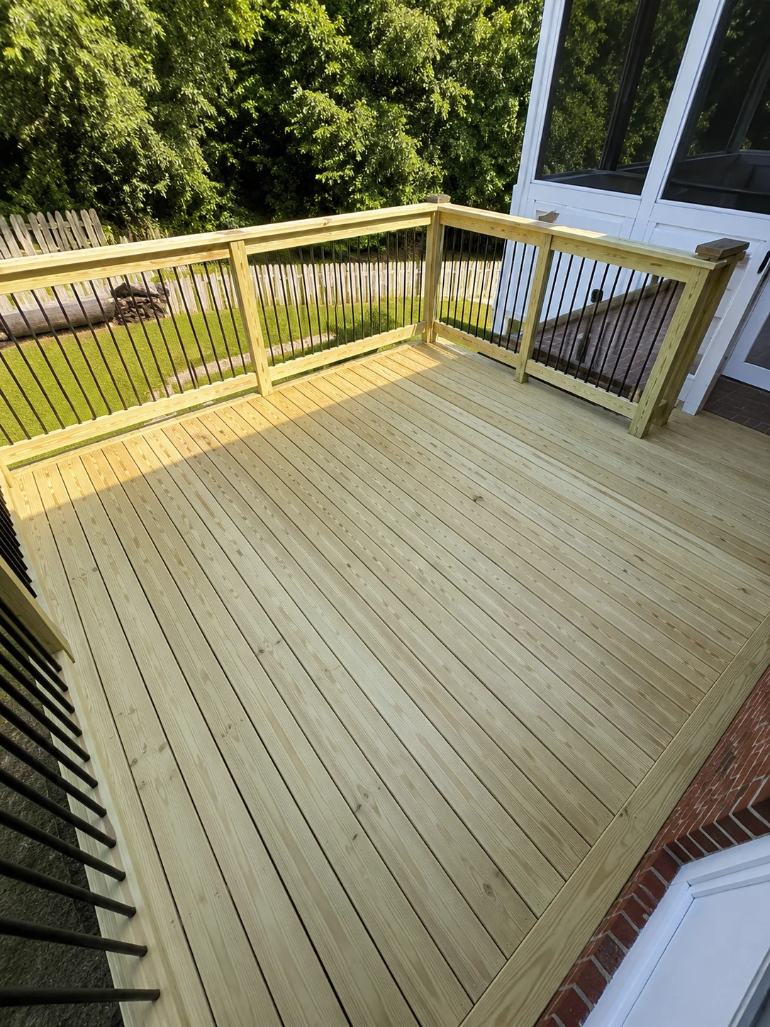 Newly built pressure-treated wood deck with composite boards and black metal railing balusters