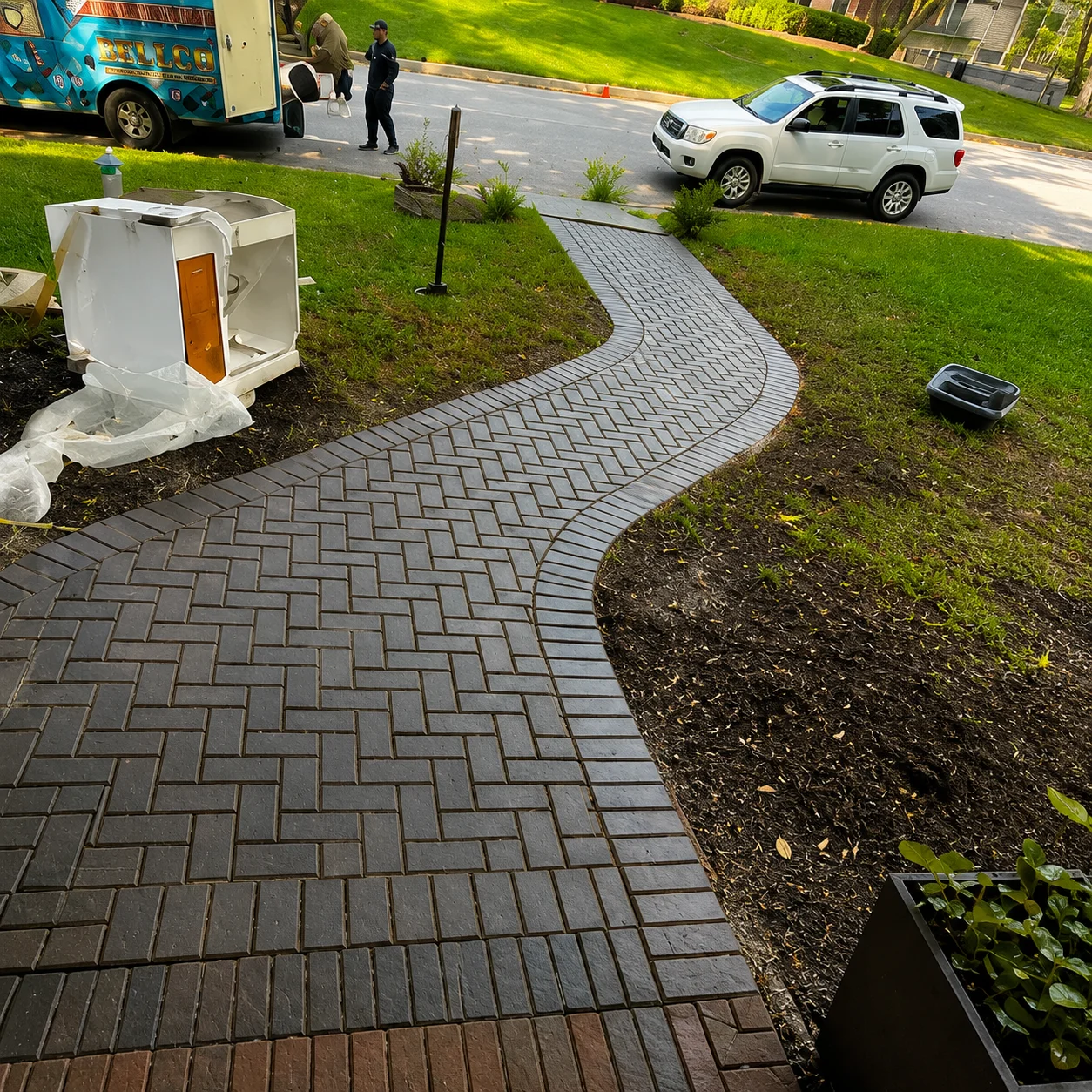Gray herringbone paver walkway with curved design and mulch bed borders